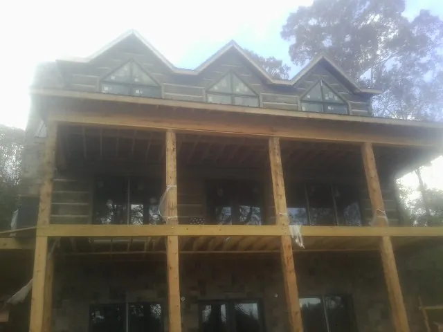 Dormers and porch framing on a large log home under construction — Roof Coating work by our crew in Menomonie