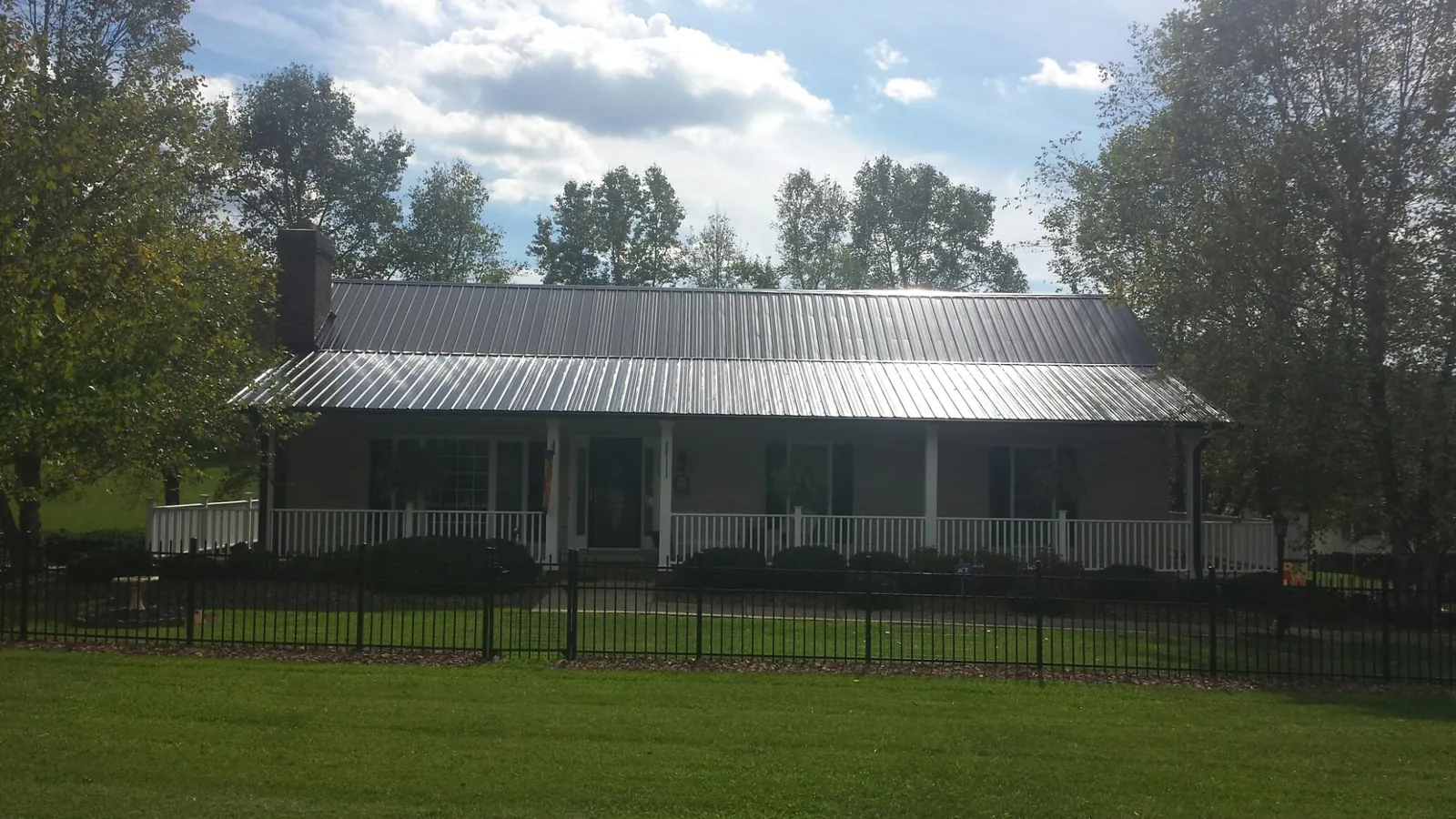 Gray metal roof on a brick ranch with a full width front porch — Gutter Guard Installation work by our crew in Menomonie