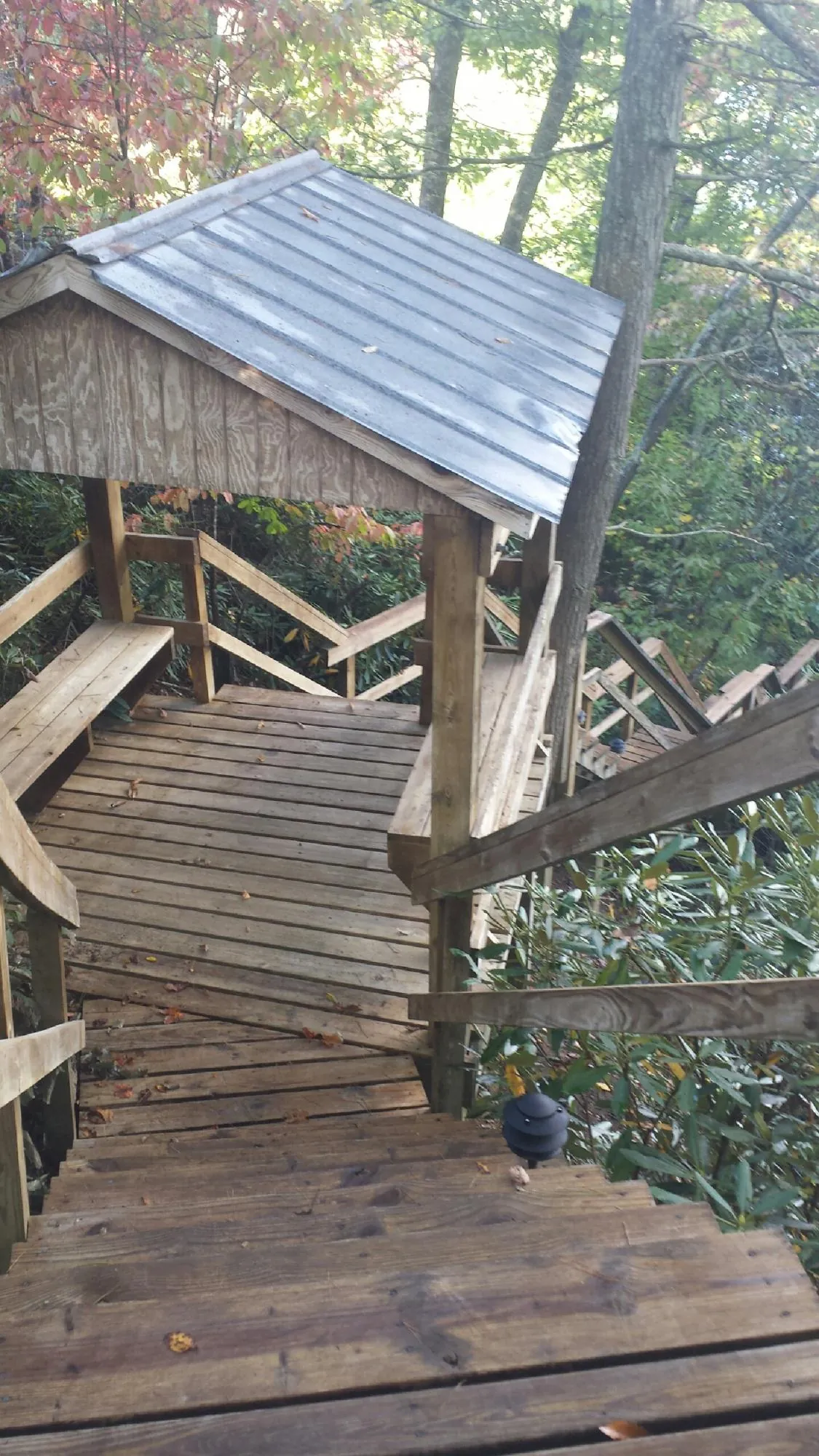 Metal roofed shelter over wooden steps on a wooded walkway — Skylight Repair & Installation work by our crew in Menomonie