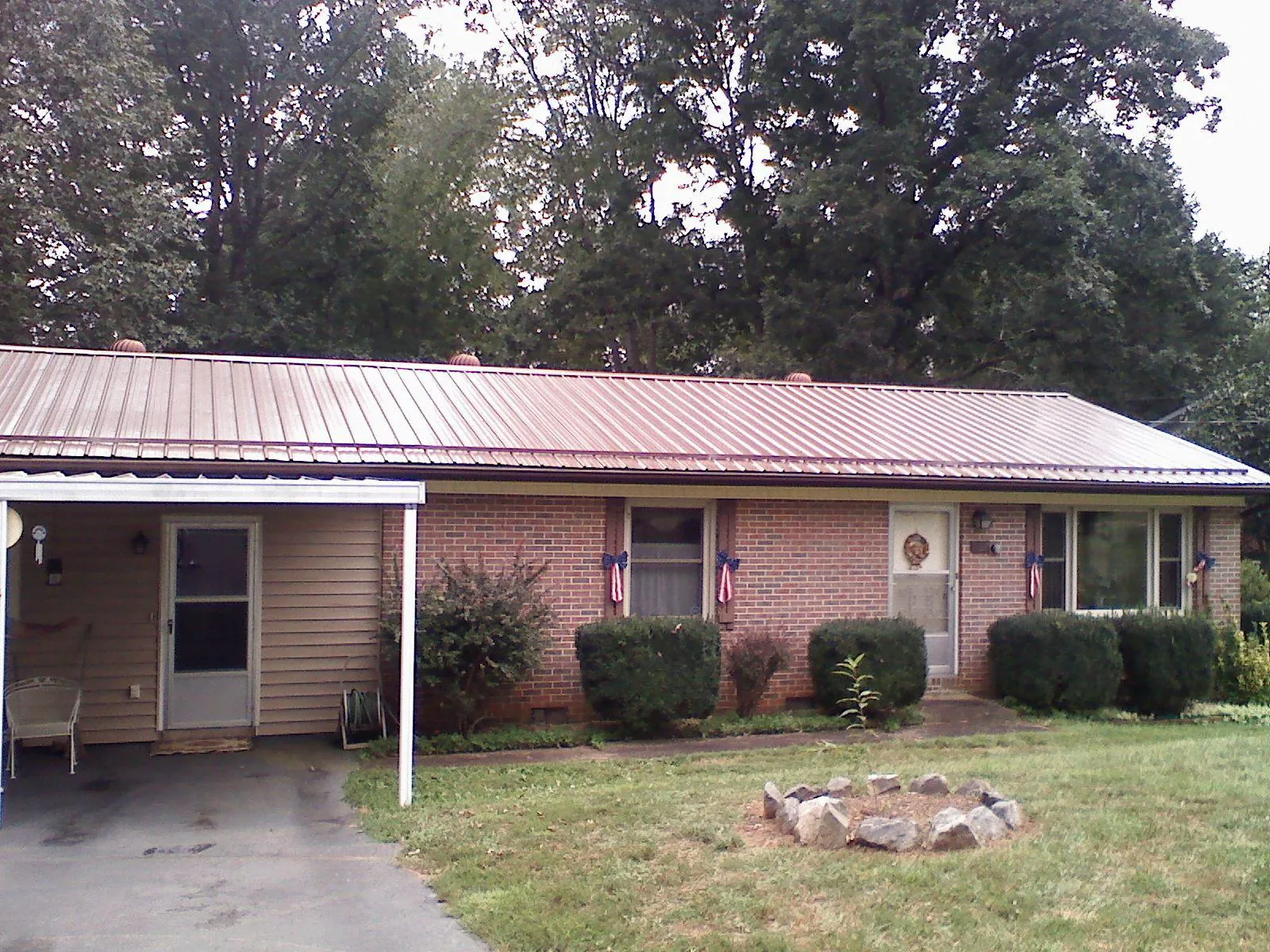 Bronze metal roof and carport on a brick ranch home — Roof Repair work by our crew in Menomonie